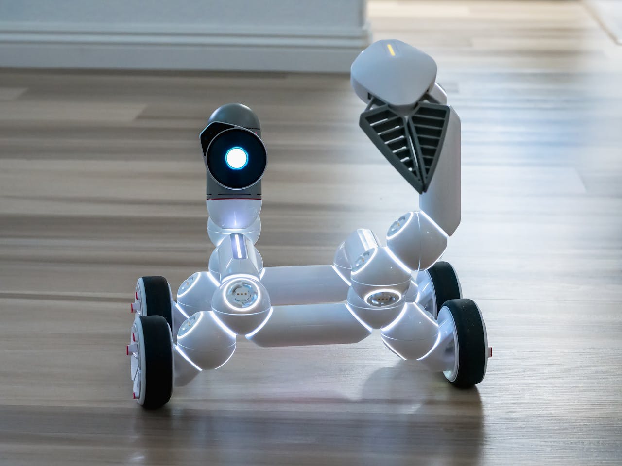 services-02 Close-up of a wheeled robot toy with a spotlight in an indoor setting, showcasing modern technology.